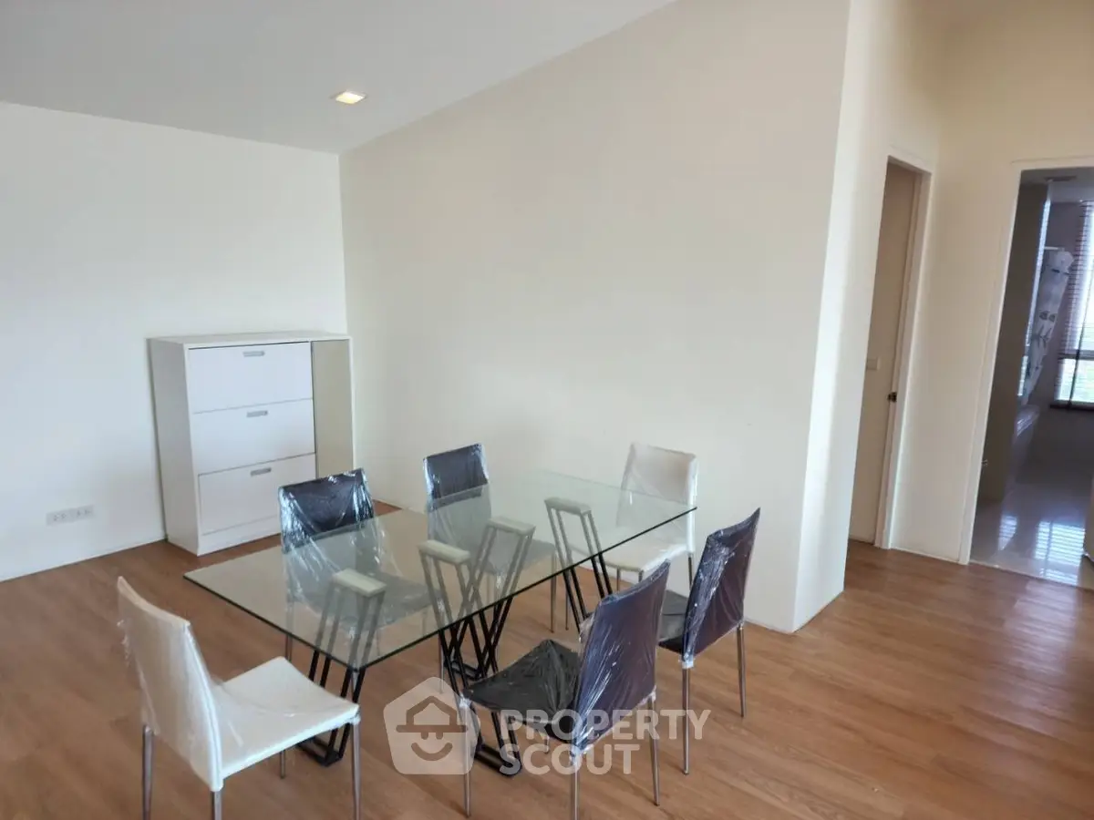 Modern dining area with glass table and stylish chairs in a bright, spacious apartment.