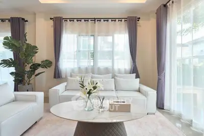 Elegant living room with white sofas, large windows, and modern decor