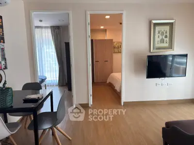 Modern apartment interior with open living area and bedroom view, featuring stylish furniture and decor.