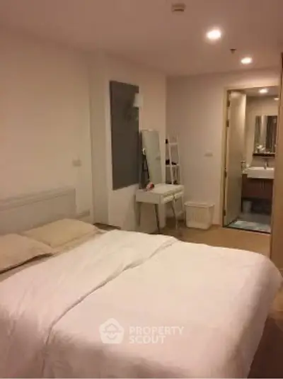 Cozy bedroom with modern decor and ensuite bathroom in a stylish apartment.