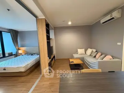Modern studio apartment with cozy living area and separate bedroom, featuring sleek wooden flooring and neutral decor.
