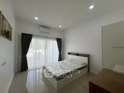 Spacious bedroom with large window and modern decor in a bright apartment.
