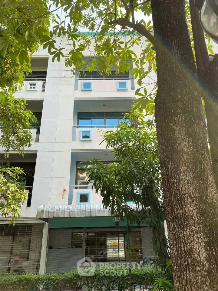 Modern apartment building exterior with lush greenery and large windows, offering a serene urban living experience.