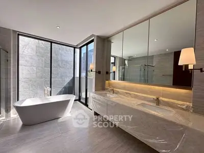 Luxurious modern bathroom with freestanding bathtub and large mirrors, featuring elegant lighting and spacious design.