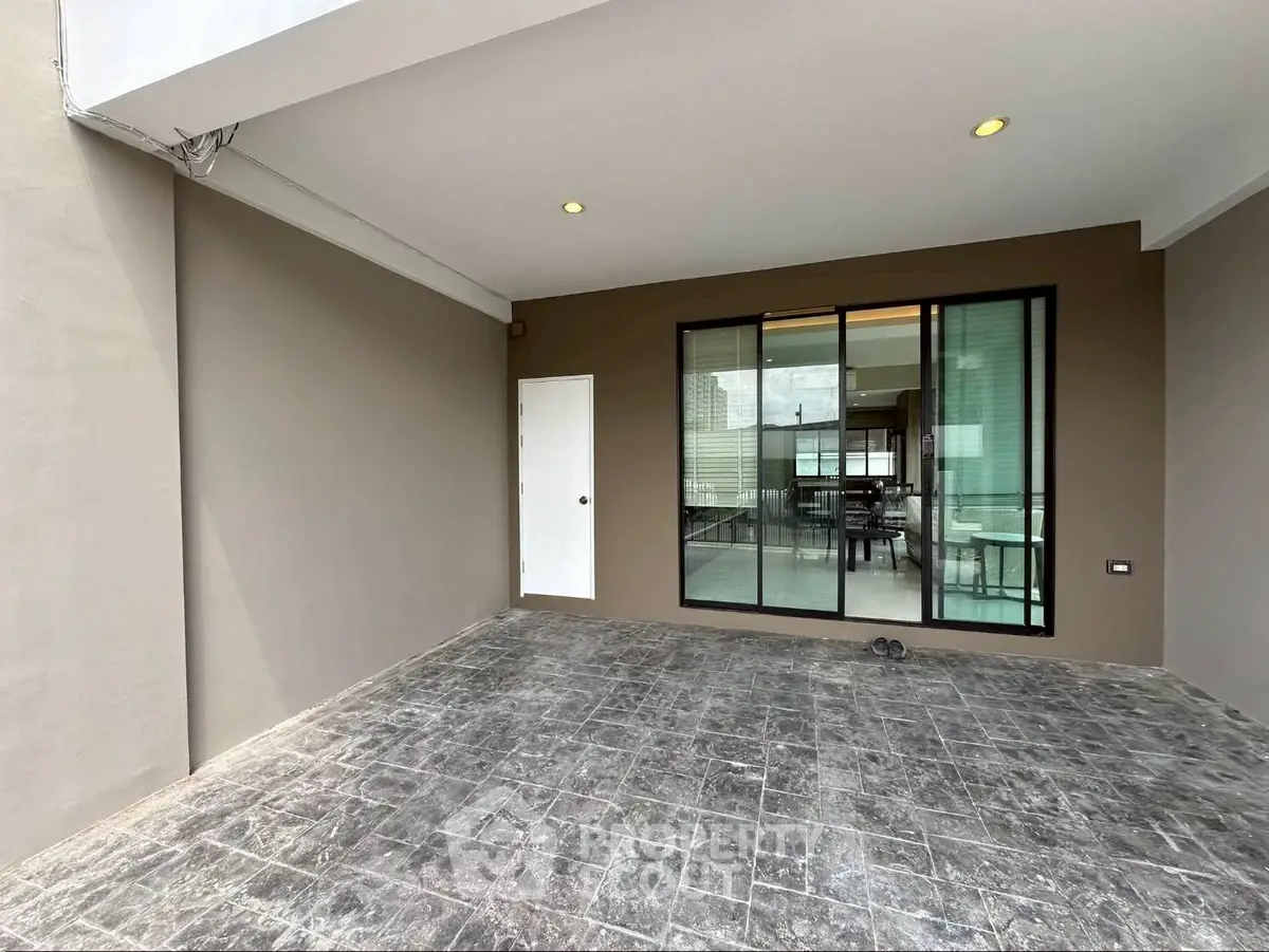 Modern home entrance with sleek sliding glass doors and spacious tiled patio.