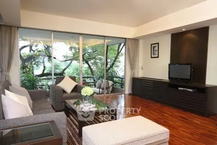 Spacious living room with modern decor and large windows overlooking greenery.