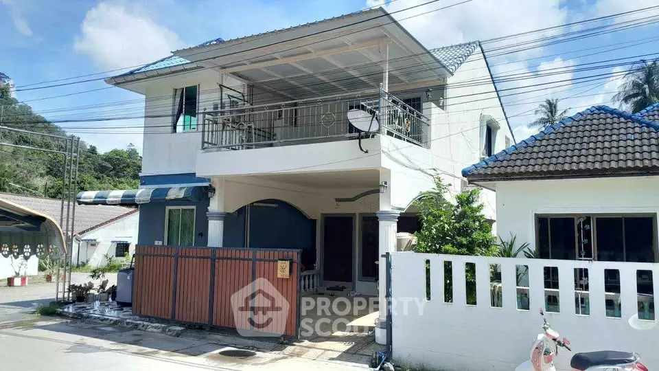 Charming two-story house with spacious balcony and gated entrance in a serene neighborhood.