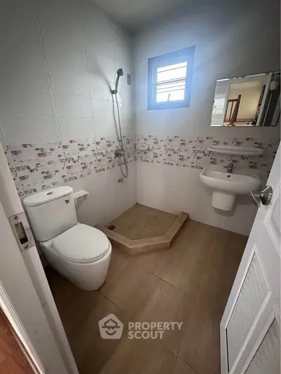 Compact bathroom with modern fixtures and a walk-in shower, featuring stylish tile accents.