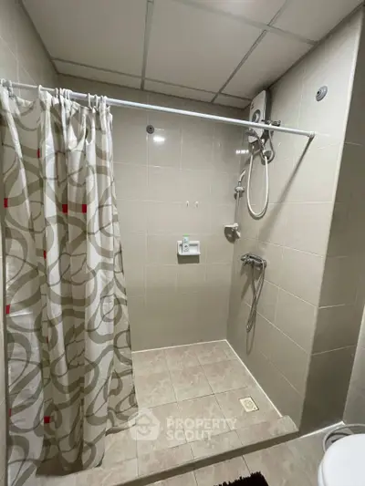 Modern bathroom with shower curtain and tiled walls, featuring a sleek showerhead and clean design.
