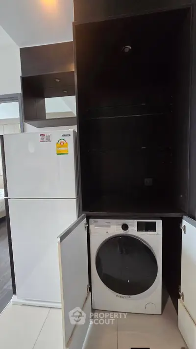 Modern kitchen with sleek appliances including fridge and washing machine in stylish cabinetry.