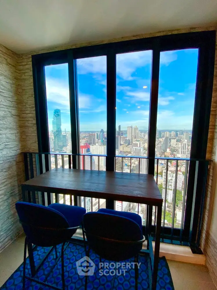 Stunning city view from high-rise balcony with modern seating area.