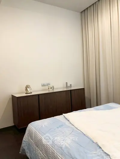 Elegant bedroom with modern decor and stylish furniture, featuring a cozy bed and sleek cabinet.