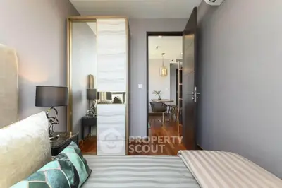 Modern bedroom with stylish decor and view into dining area, featuring elegant lighting and hardwood floors.