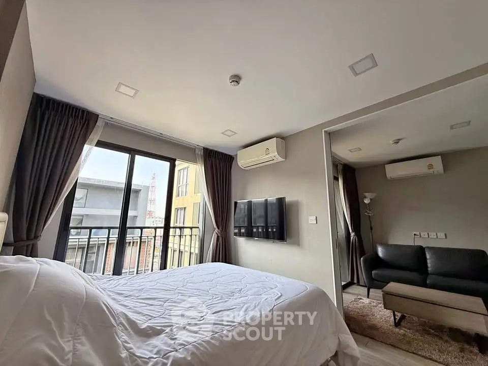 Modern bedroom with balcony view and cozy living area in stylish apartment