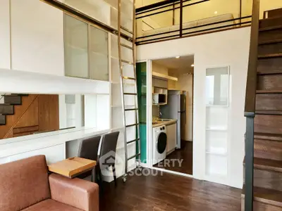 Modern loft apartment with mezzanine, stylish furniture, and compact kitchen featuring washing machine.