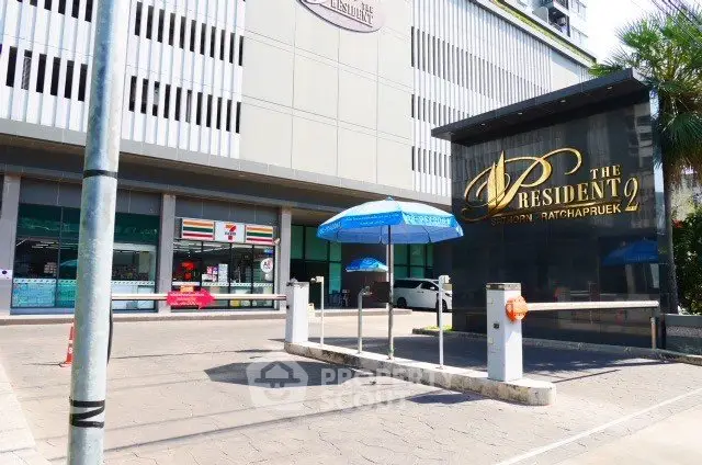 Modern condominium entrance with retail shops and parking area, ideal urban living location.