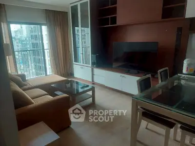 Modern living room with large TV and city view balcony in high-rise apartment.