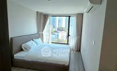 Modern bedroom with large window offering city view, featuring a cozy bed and air conditioning.