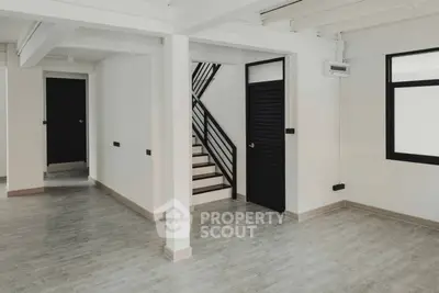 Spacious and modern living area with elegant staircase, sleek flooring, and ample natural light, perfect for stylish urban living.