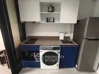 Modern compact kitchen with washing machine, microwave, and fridge in sleek design.