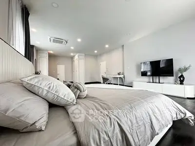 Spacious modern bedroom with sleek design and large TV