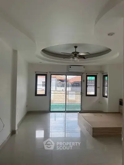 Spacious living room with modern ceiling fan and large windows for natural light.