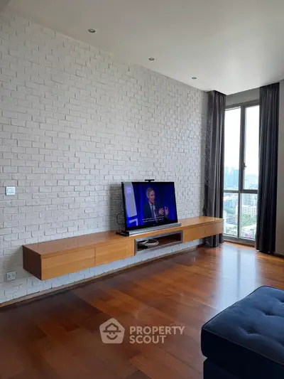 Spacious modern living room with brick accent wall and large window offering city views.