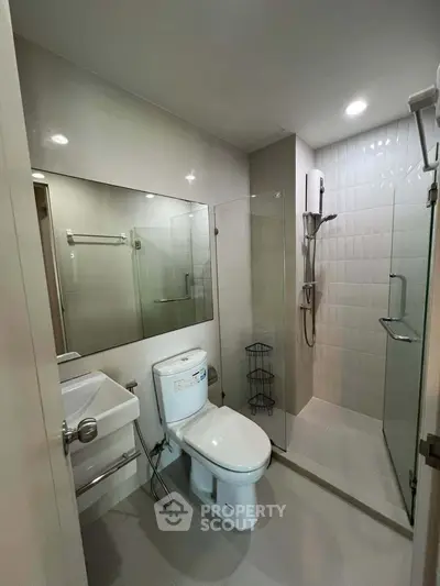 Modern bathroom with glass shower enclosure and sleek fixtures in a contemporary apartment.