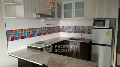 Modern kitchen with colorful backsplash and sleek appliances in a stylish apartment.