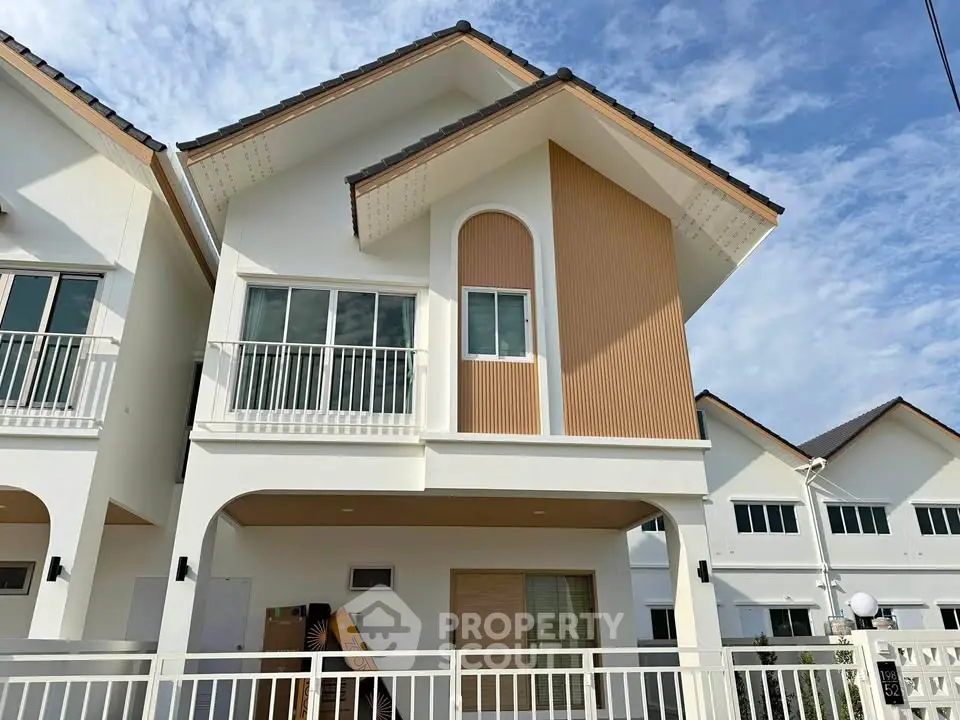 Modern two-story house with stylish facade and large windows in a sunny neighborhood.
