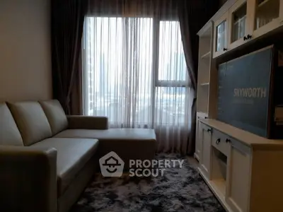 Cozy living room with modern sofa and entertainment unit, featuring large windows with sheer curtains.