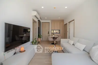 Modern living room with sleek furniture and open layout, featuring a cozy sofa and large TV.