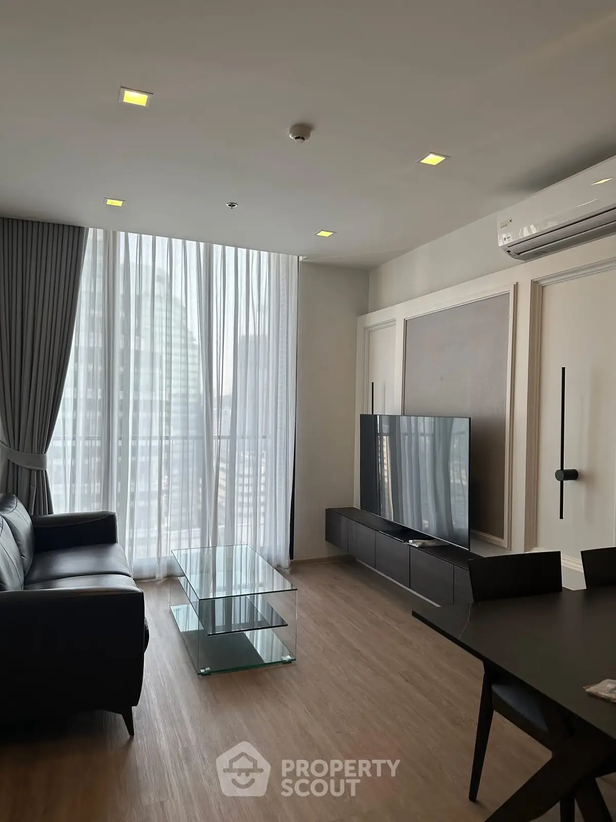 Modern living room with sleek furniture and large window offering city view, perfect for urban living.