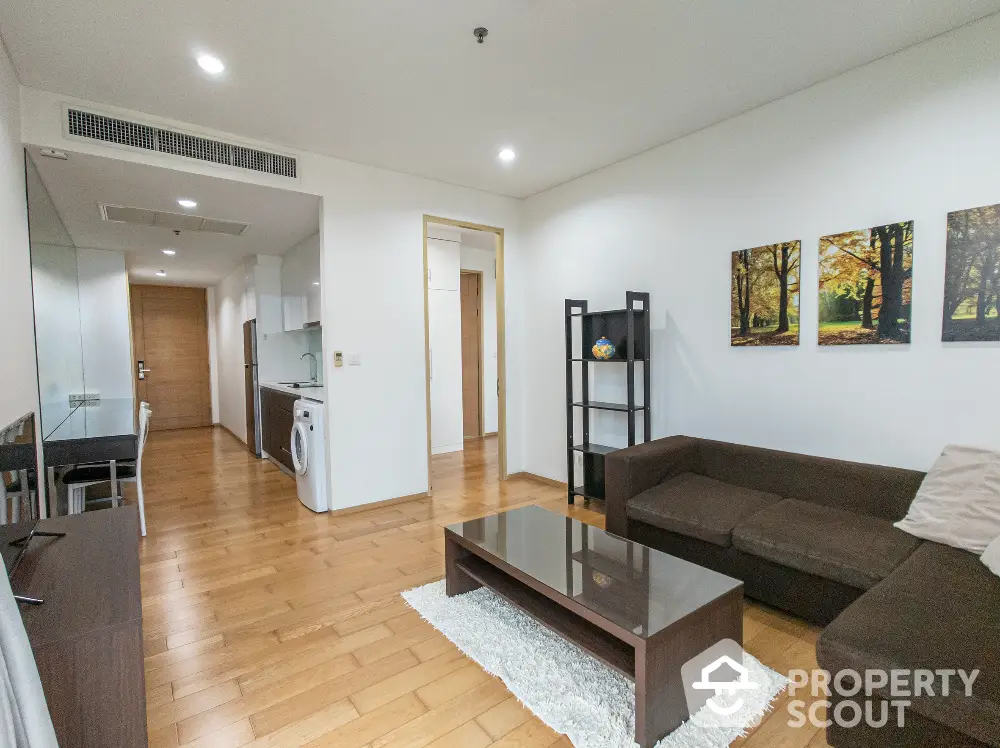 Modern living room with hardwood floors, cozy sofa, and open kitchen layout in a stylish apartment.