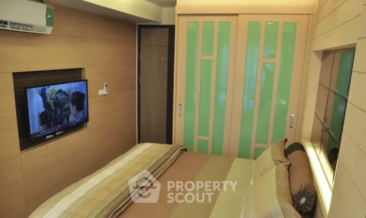 Cozy bedroom with modern design and built-in TV, featuring stylish sliding closet doors.