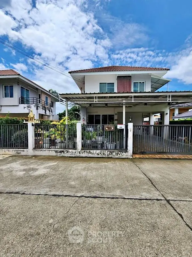 Charming two-story house with gated front yard and carport in a suburban neighborhood.