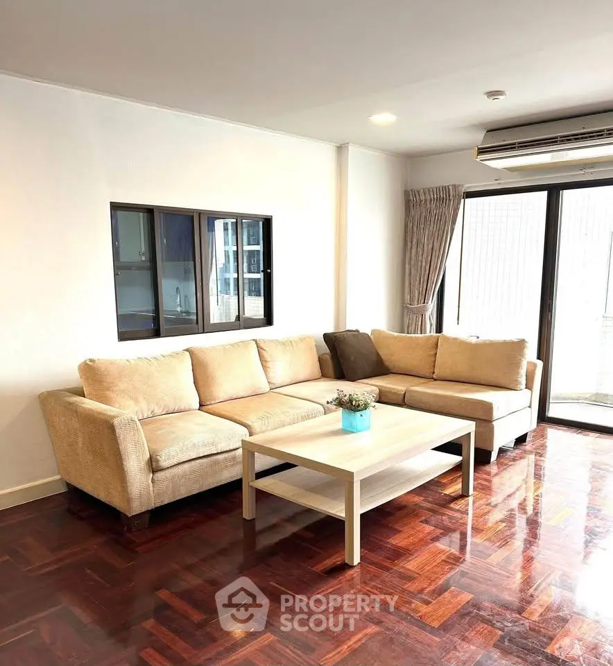 Spacious living room with elegant parquet flooring and cozy beige sofa, perfect for relaxation.