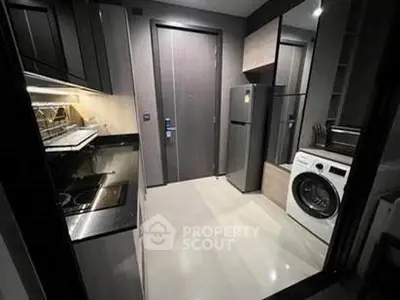 Modern kitchen with sleek appliances and washing machine in compact layout.