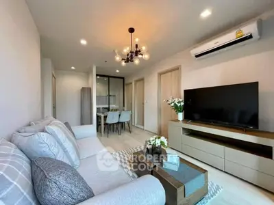 Elegant living room seamlessly connects to a cozy dining area, featuring modern furnishings, tasteful decor, and ample natural light for a welcoming atmosphere.