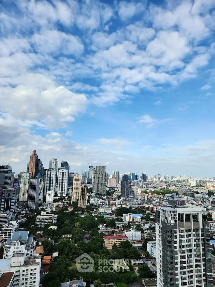 Stunning cityscape view from high-rise building with blue sky and clouds.