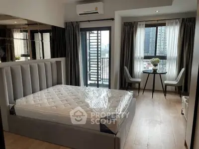 Modern bedroom with balcony and city view, featuring stylish decor and natural light.