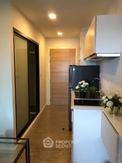Modern kitchen with sleek cabinetry and stylish decor in a compact apartment layout.