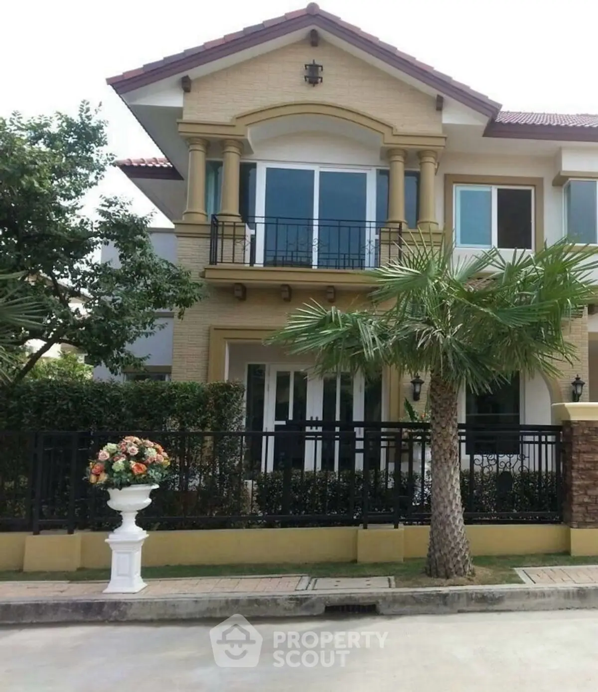 Elegant two-story house with balcony and lush greenery