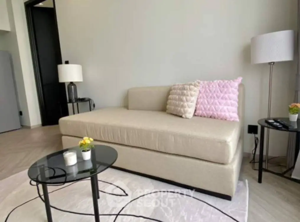 Chic modern living room with a plush cream sofa, elegant floor lamp, and a sleek black coffee table, accented by a stylish area rug.