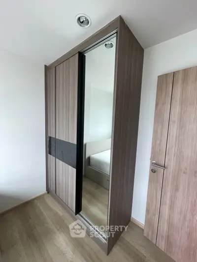 Modern bedroom with sleek mirrored wardrobe and wooden flooring