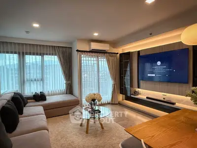 Modern living room with large TV, cozy sectional sofa, and elegant decor.