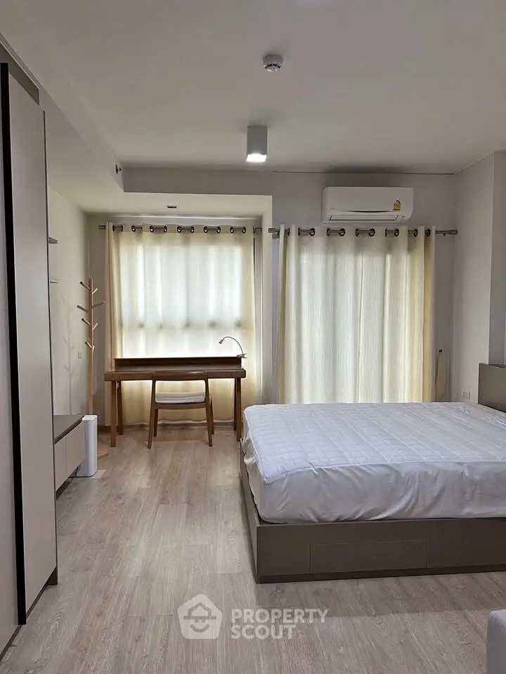 Modern bedroom with natural light, featuring a cozy bed, stylish desk, and elegant curtains.