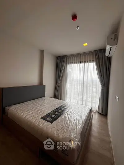 Spacious bedroom with large window and modern furnishings in a stylish apartment.