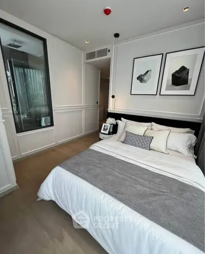 Modern bedroom with elegant decor and large window, featuring stylish artwork and cozy bedding.