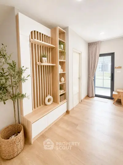 Modern interior with wooden flooring, stylish shelving, and natural light from glass door.